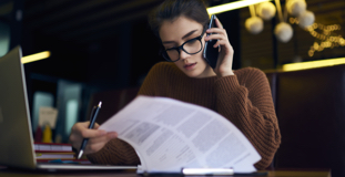 Une femme révisant de la documentation personnelle sur la faillite pendant qu'elle parle au téléphone